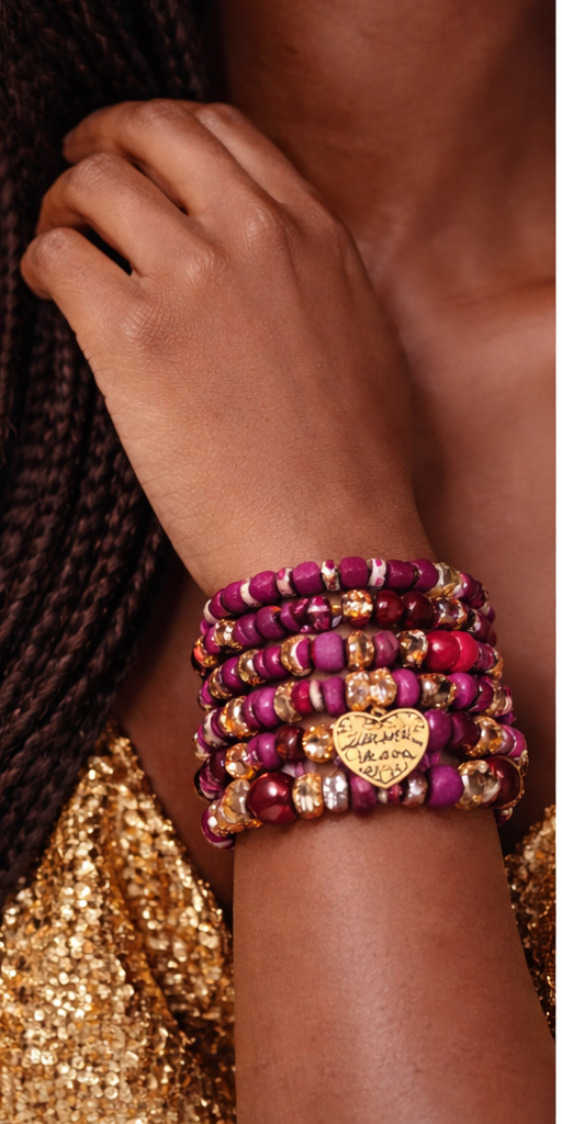Bracelets fuchsia et dorés portés au poignet sur peau foncée