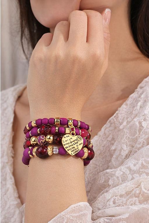 Ensemble de bracelets fuchsia et dorés porté au poignet