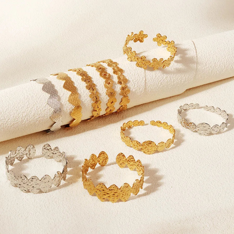 Bracelets joncs à motifs floraux dorés et argentés présentés sur et autour d’un support blanc