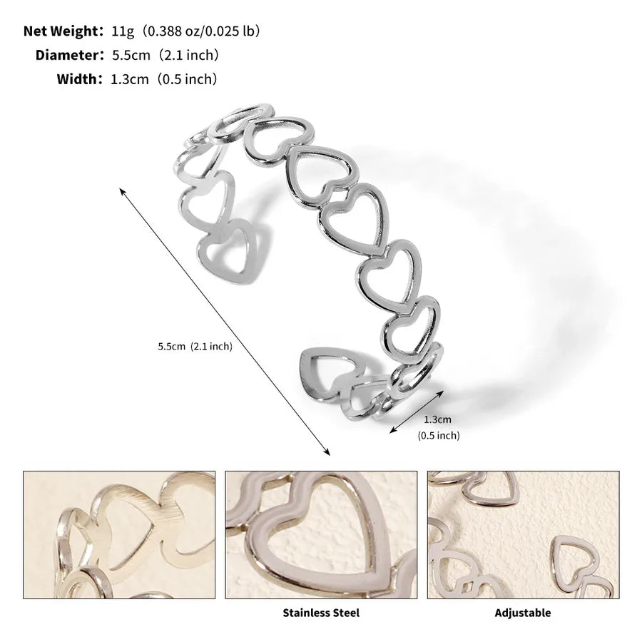 Bracelet manchette argenté ouvert composé de cœurs ajourés ; l’image indique 5,5 cm de diamètre et 1,3 cm de largeur