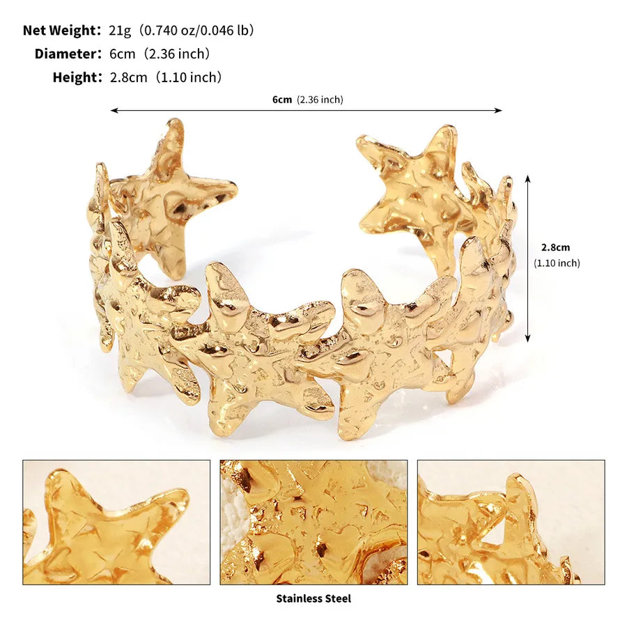 Bracelet manchette doré ouvert à motifs d’étoiles de mer ; l’image indique 6 cm de diamètre et 2,8 cm de hauteur