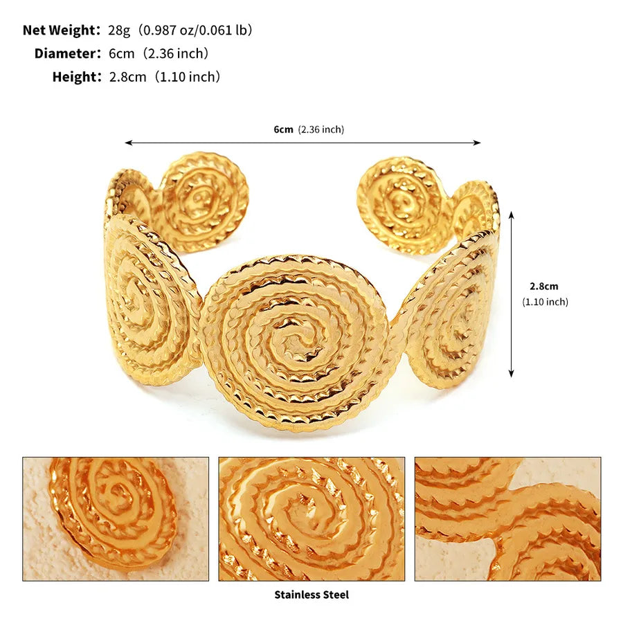 Bracelet manchette doré ouvert composé de grands motifs en spirale texturée ; l’image indique 6 cm de diamètre et 2,8 cm de hauteur